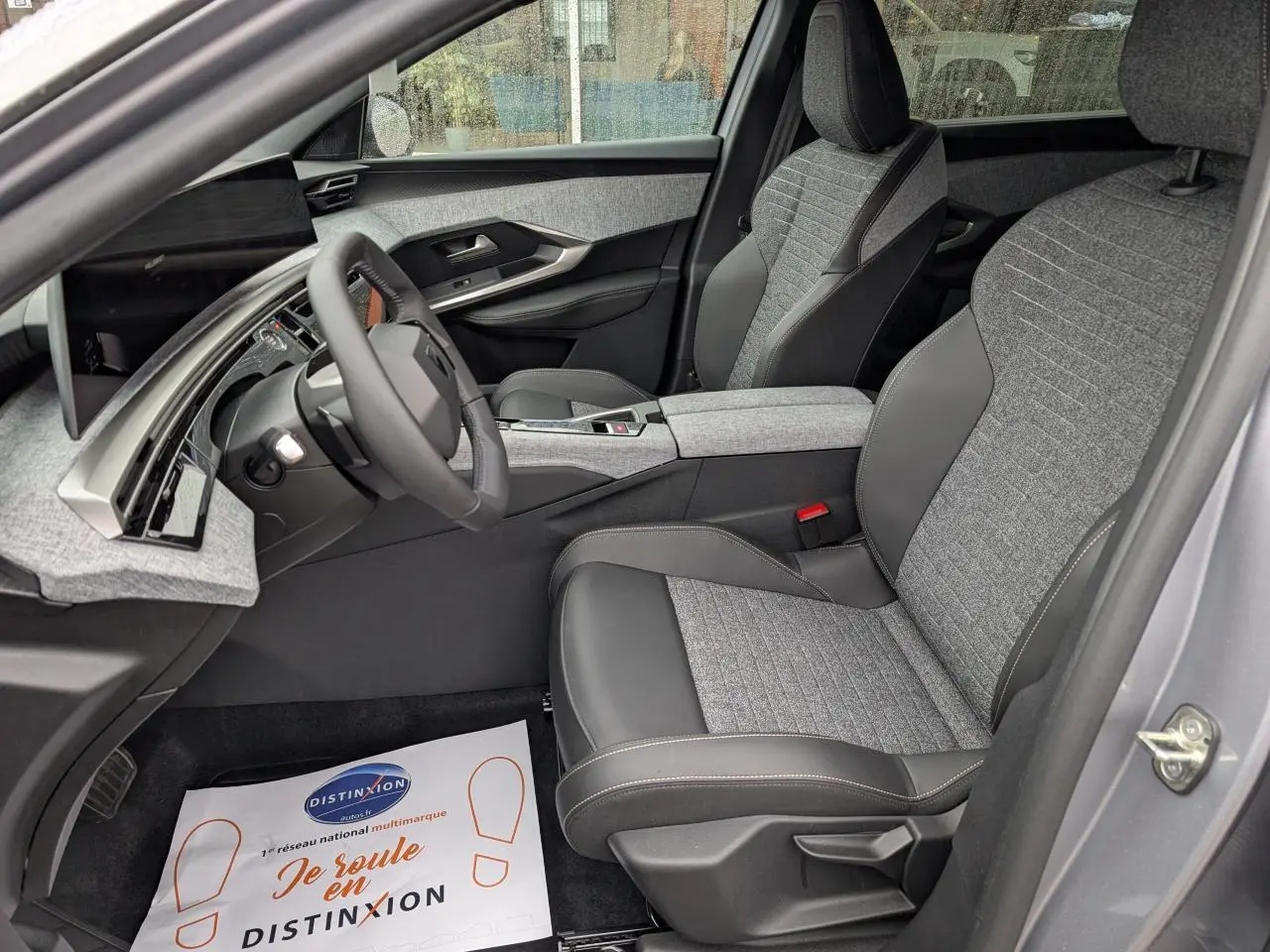 Intérieur côté conducteur du Peugeot 5008 gris Artense 2025, sièges tissu gris et cuir noir, tableau de bord moderne avec écran incurvé.
