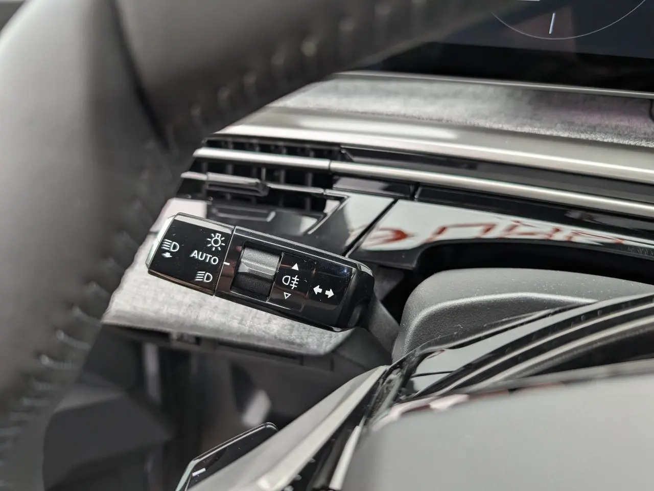 Gros plan sur la commande des feux et clignotants à gauche du volant du Peugeot 5008 gris Artense 2025.