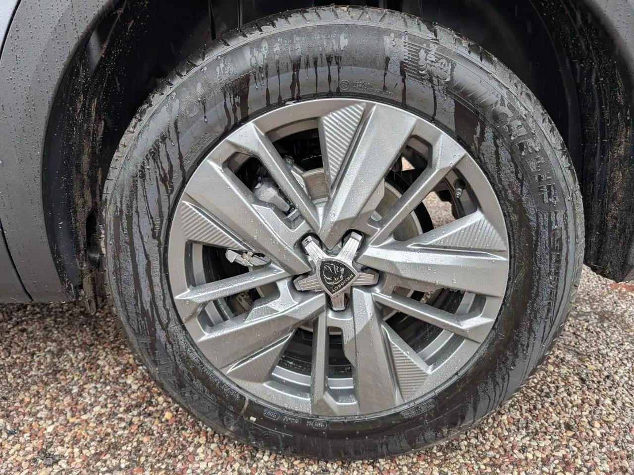 Gros plan sur la jante alliage 19'' diamantée noire du PEUGEOT 5008 Gris Artense avec pneu Michelin humide.