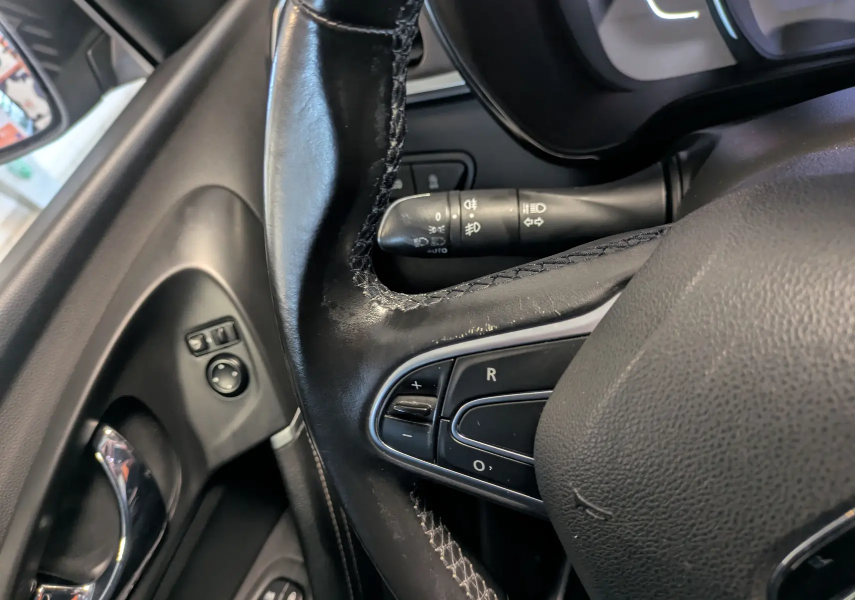 Gros plan sur le volant en cuir noir et les commandes de régulateur de vitesse du Renault Kadjar gris, côté conducteur.