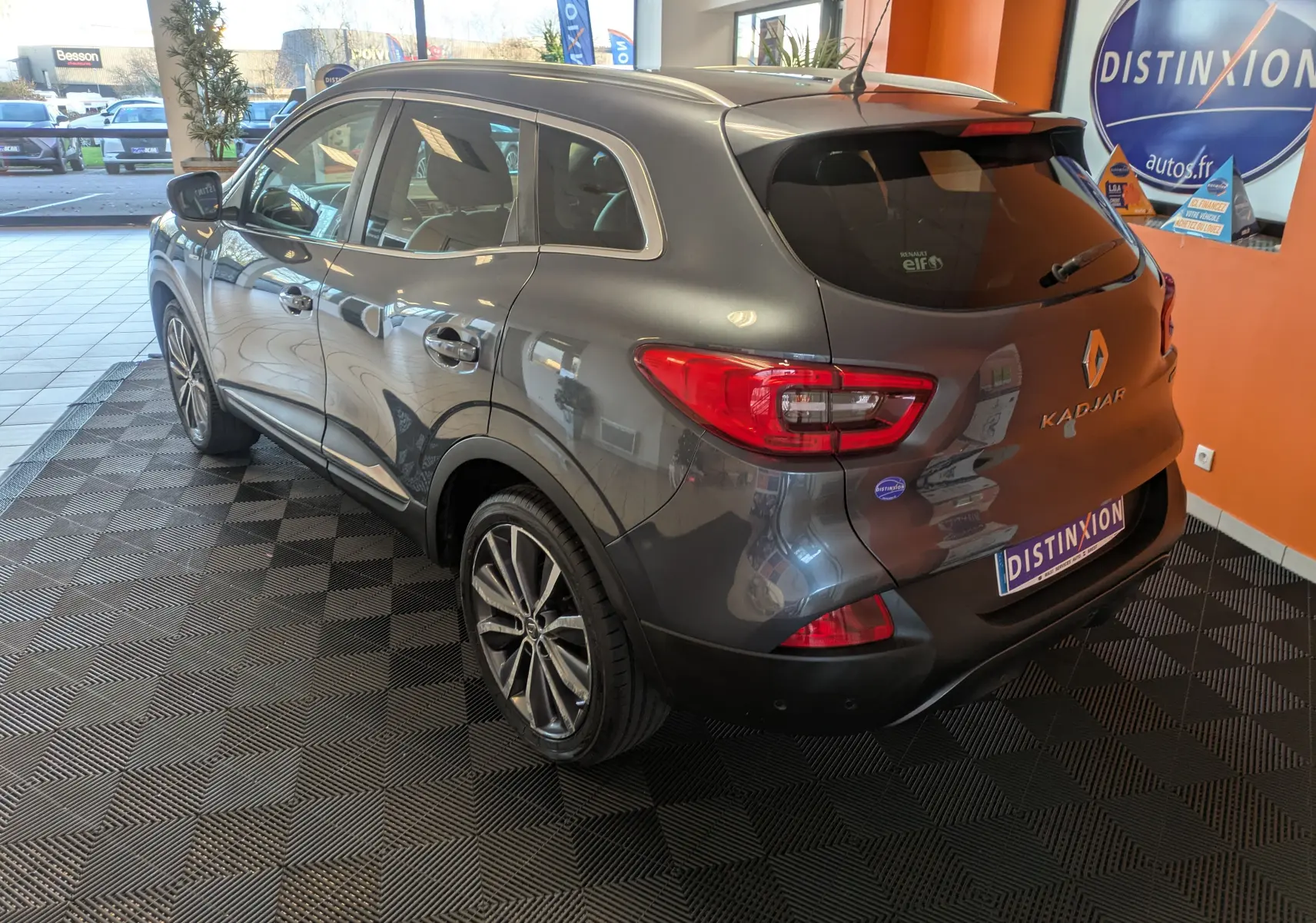Renault Kadjar gris 3/4 arrière droit en showroom, mettant en valeur ses feux arrière et jantes alliage biton.