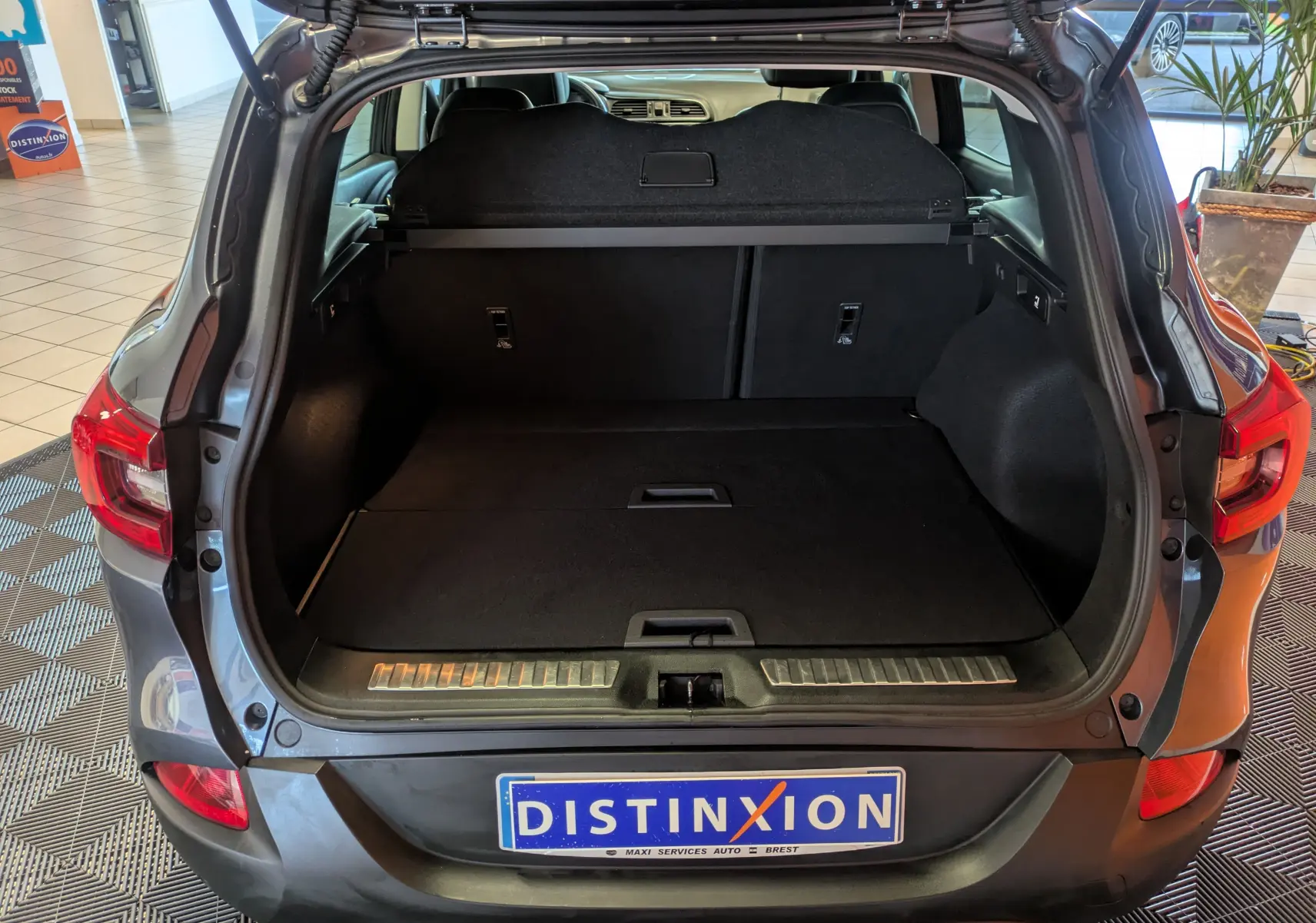 Coffre ouvert vu de l'arrière d'un Renault Kadjar gris 2017, montrant un espace de chargement spacieux et propre.