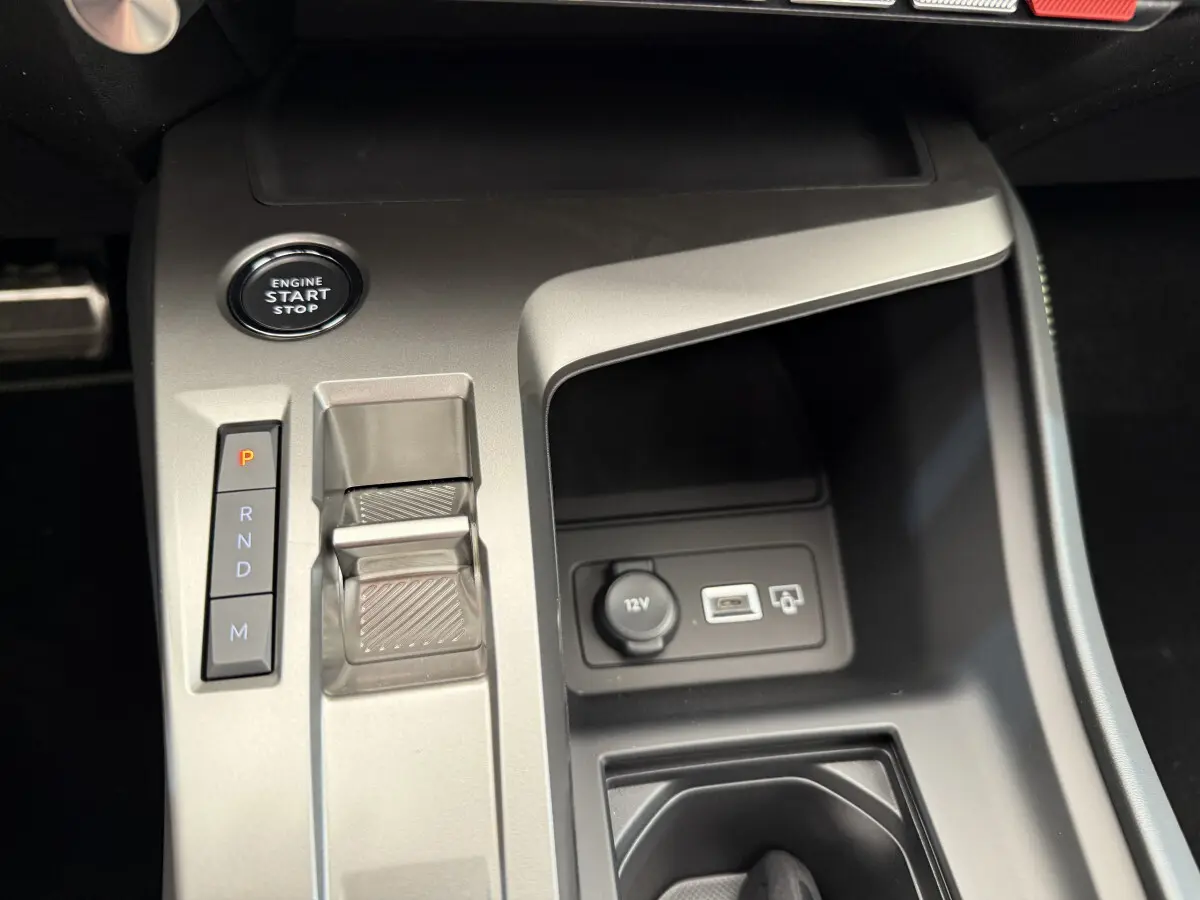 Gros plan sur la console centrale grise du Peugeot 308 Hybrid 136 e-DCS6 GT avec bouton start/stop et commandes boîte auto.