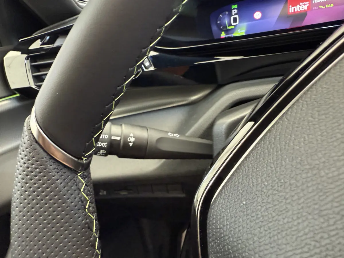 Gros plan sur le volant cuir noir avec coutures contrastantes et le combiné d'instruments digital de la Peugeot 308 Hybrid 2024.