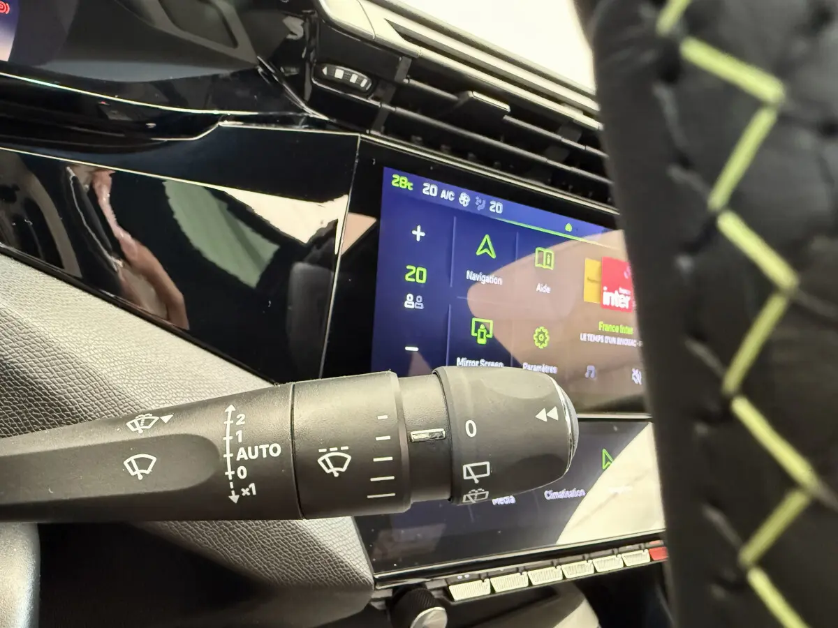 Gros plan sur la commande d’essuie-glace et l’écran tactile central du tableau de bord de la Peugeot 308 Hybrid gris foncé.