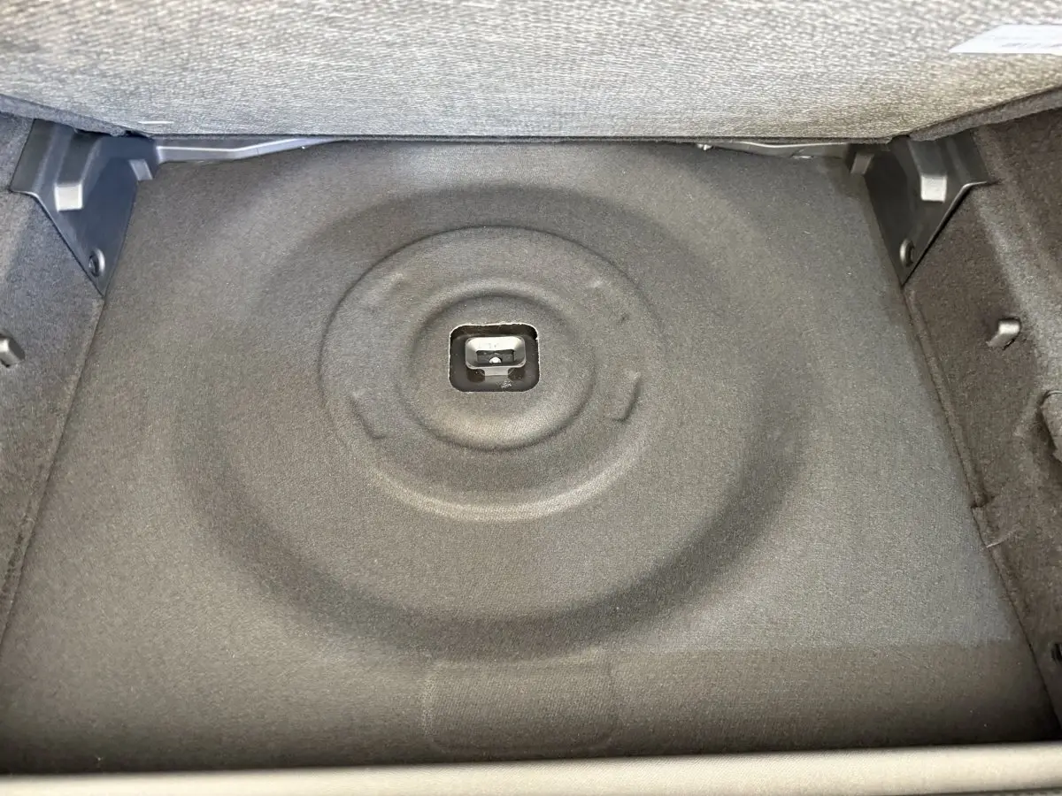 Vue rapprochée du coffre de la Peugeot 308 Hybrid 136 e-DCS6 GT 2024, montrant le compartiment gris foncé pour roue de secours.