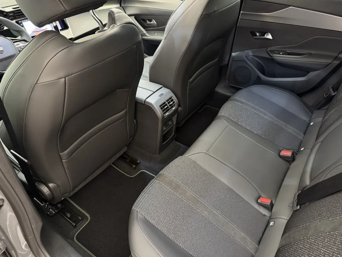 Vue intérieure arrière côté droit de la Peugeot 308 Hybrid gris foncé, montrant les sièges en cuir et tissu et la console centrale.