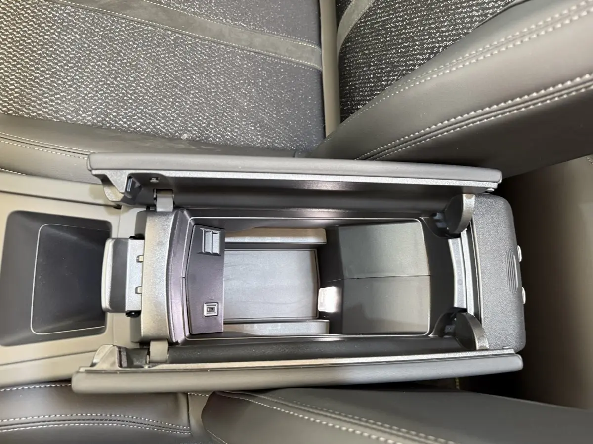 Vue plongeante sur l'accoudoir central ouvert en cuir gris foncé de la Peugeot 308 Hybrid 136 e-DCS6 GT 2024.