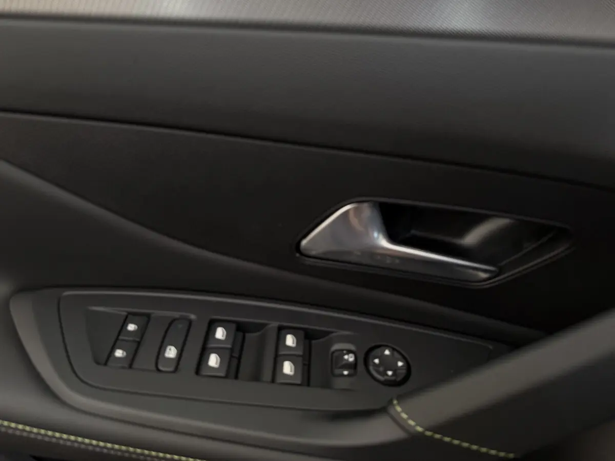 Détail intérieur montrant la commande des vitres et la poignée de porte côté conducteur d’une Peugeot 308 Hybrid 2024 gris foncé.
