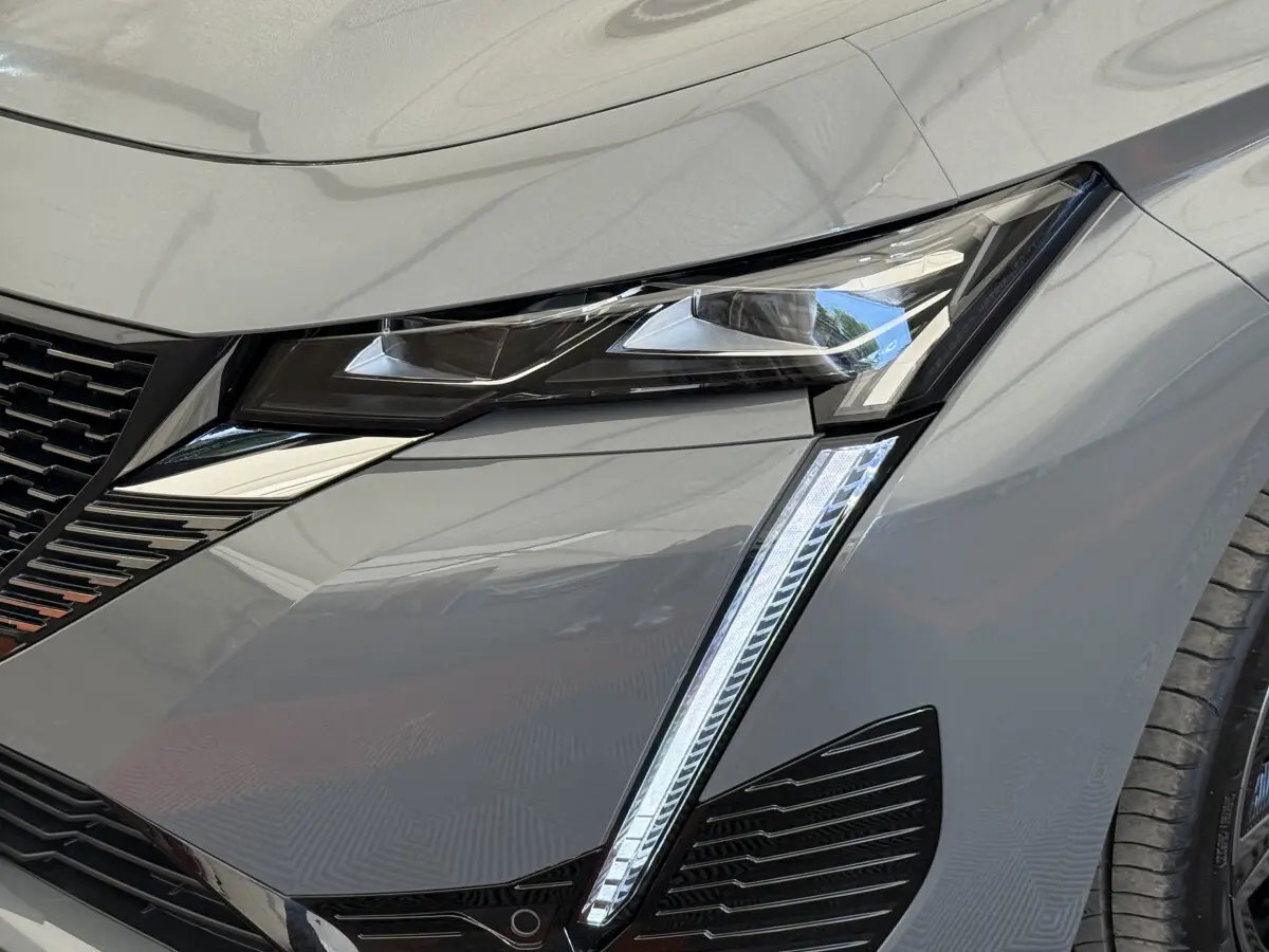 Gros plan sur le phare avant droit gris foncé du Peugeot 308 Hybrid 136 e-DCS6 GT 2024 avec éclairage LED distinctif.