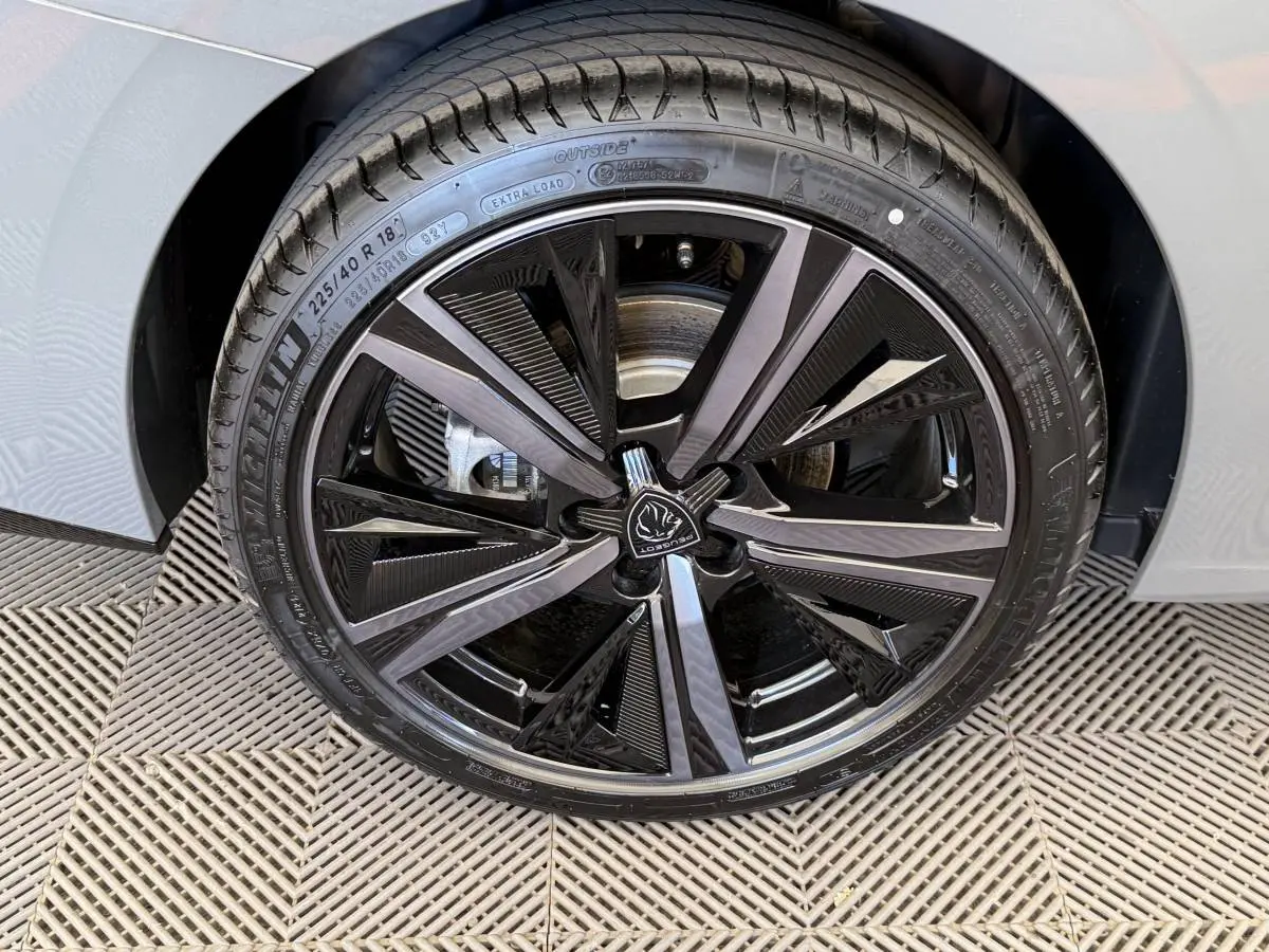 Gros plan sur la roue avant droite de la Peugeot 308 Hybrid gris foncé, avec jante alliage noire et argentée au design moderne.