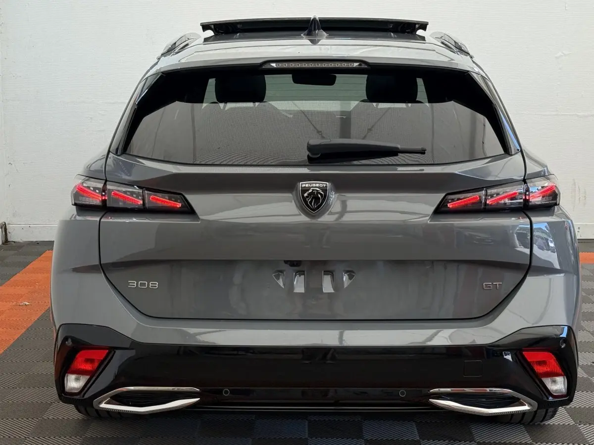 Vue arrière d’une Peugeot 308 GT gris foncé avec feux LED allumés et double sortie d’échappement chromée.