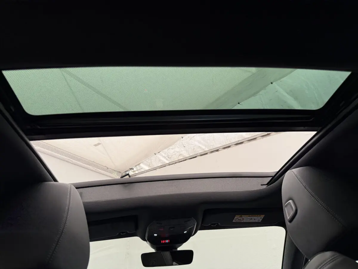 Vue intérieure du toit ouvrant panoramique et des appuie-têtes en cuir gris foncé d'une Peugeot 308 Hybrid 2024.