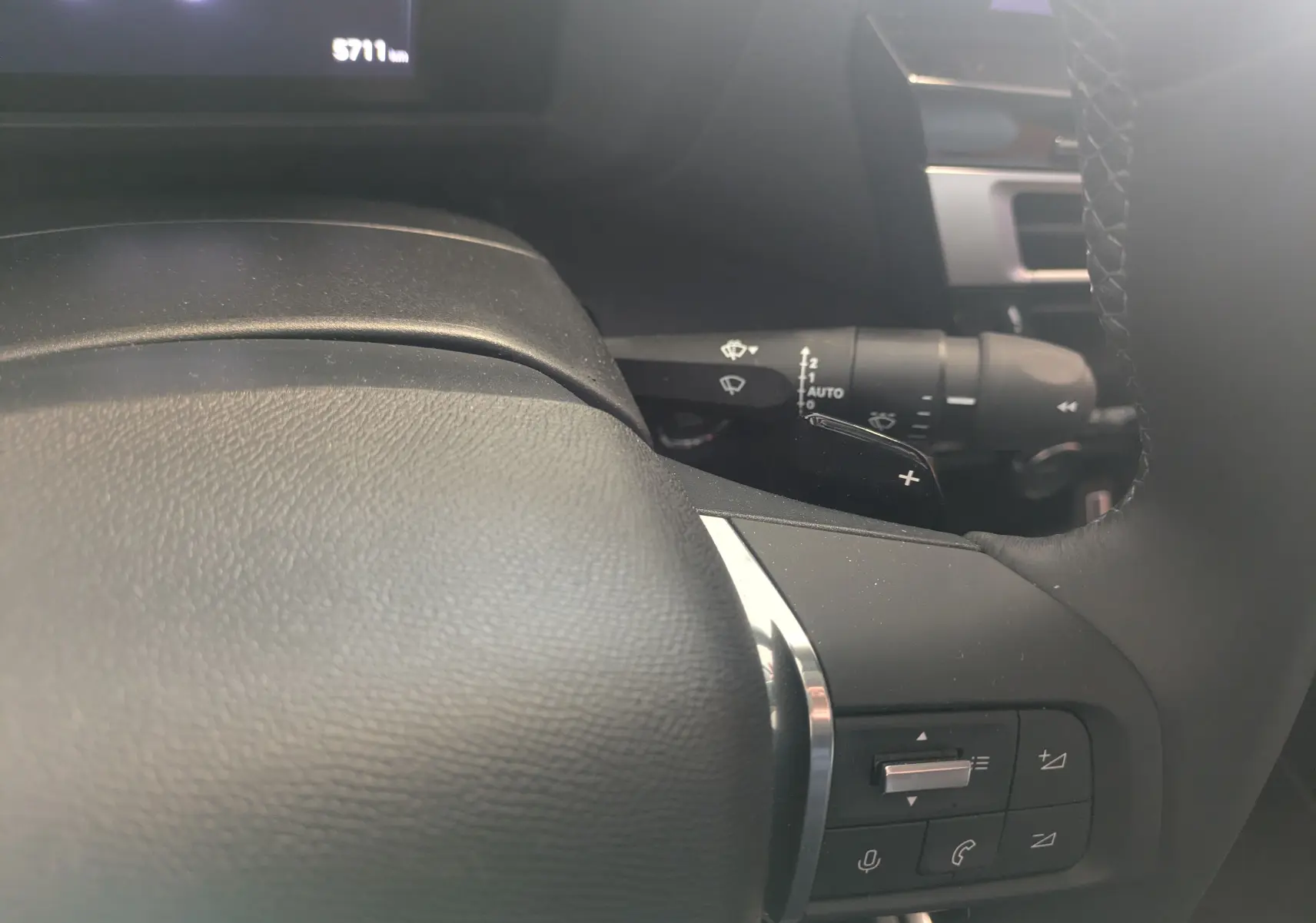 Gros plan sur le volant cuir noir avec commandes intégrées et manette de clignotant du Citroën C4 hybride 2025.