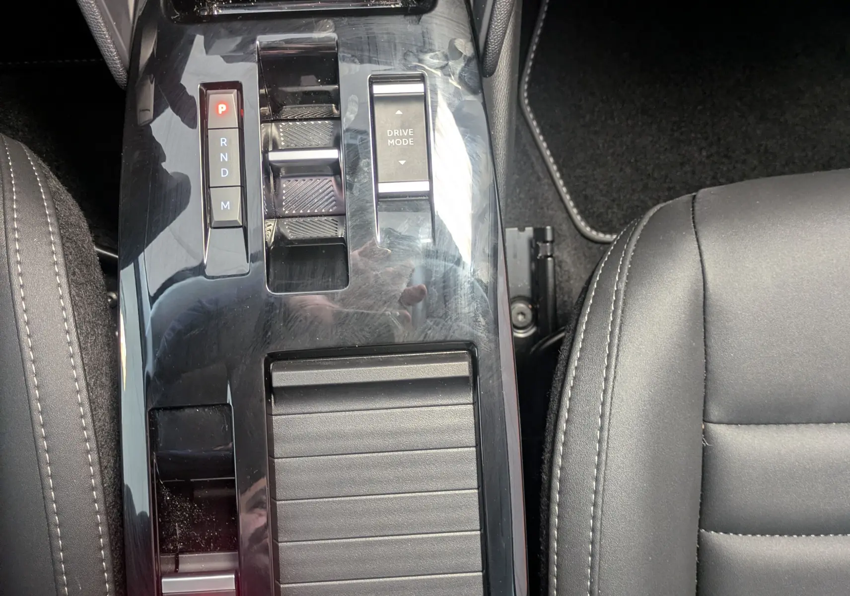 Vue plongeante sur la console centrale noire brillante avec sélecteur de boîte auto et bouton Drive Mode du Citroën C4 hybride.