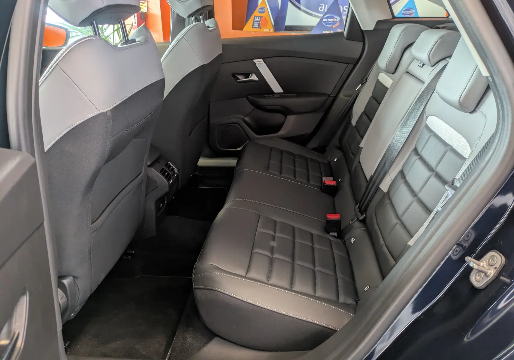 Vue intérieure côté droit des sièges arrière en cuir noir et gris clair du Citroën C4 Hybride 2025 Bleu Eclipse.