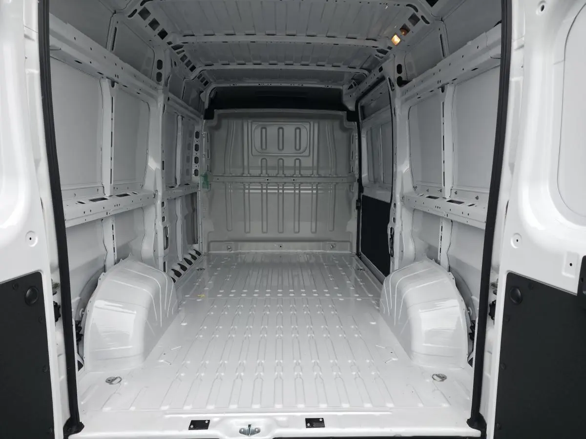 Vue intérieure arrière du fourgon Peugeot Boxer blanc, montrant l'espace de chargement tôlé vide et lumineux.