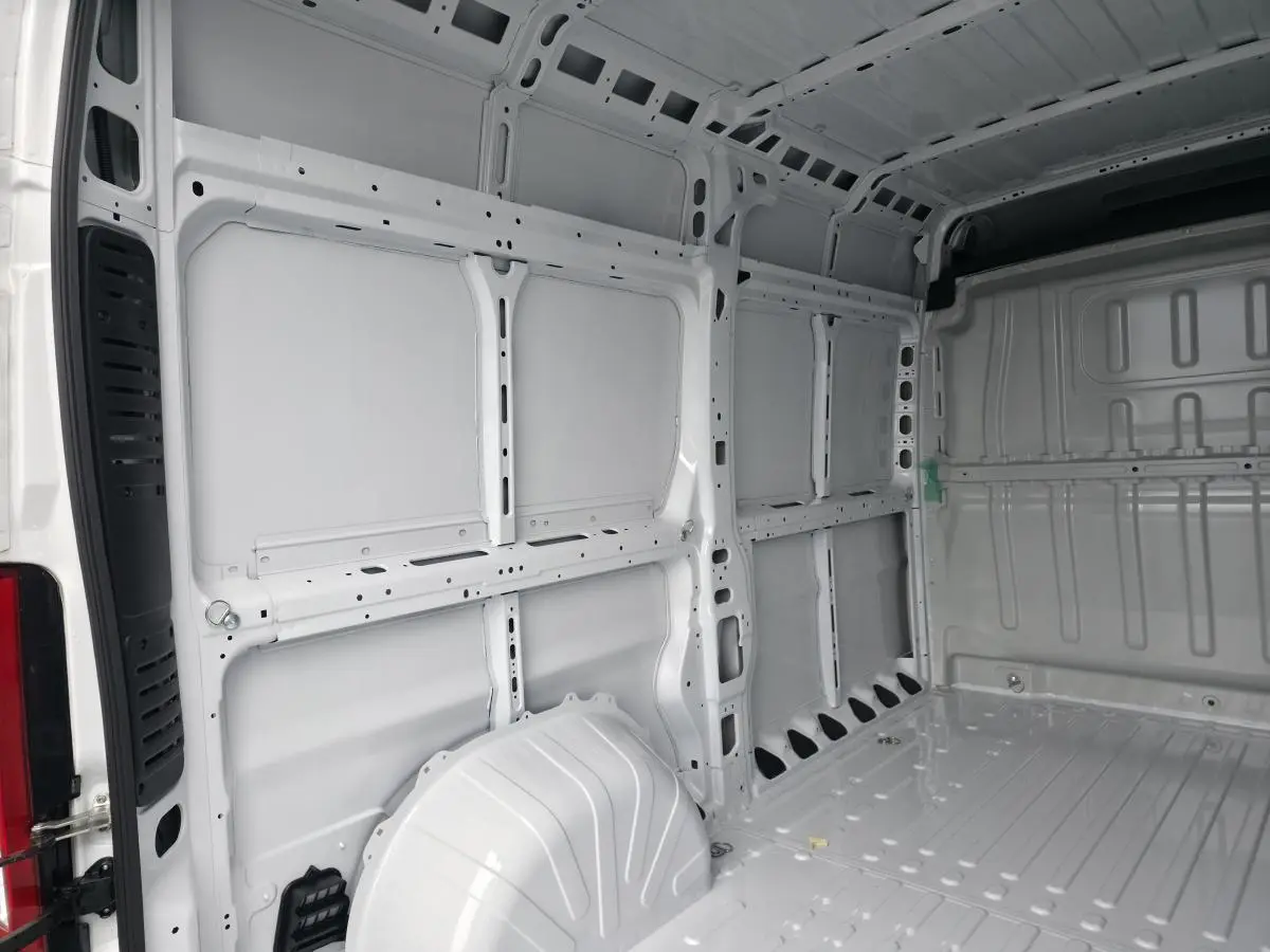 Intérieur du fourgon Peugeot Boxer blanc vu de l'arrière, montrant la structure tôlée et l'espace de chargement vide.