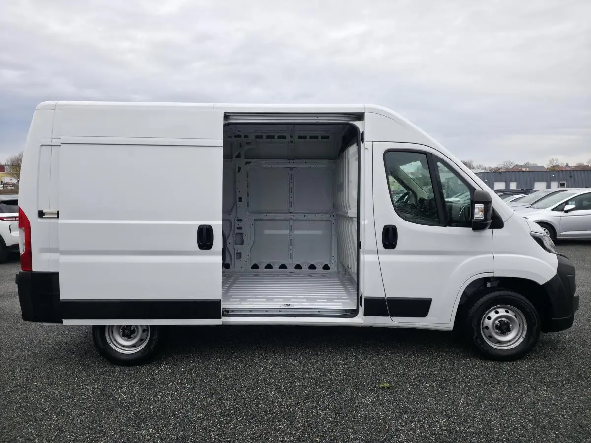 Vue latérale droite d'un Peugeot Boxer Fourgon blanc avec porte coulissante ouverte montrant l'espace de chargement vide.