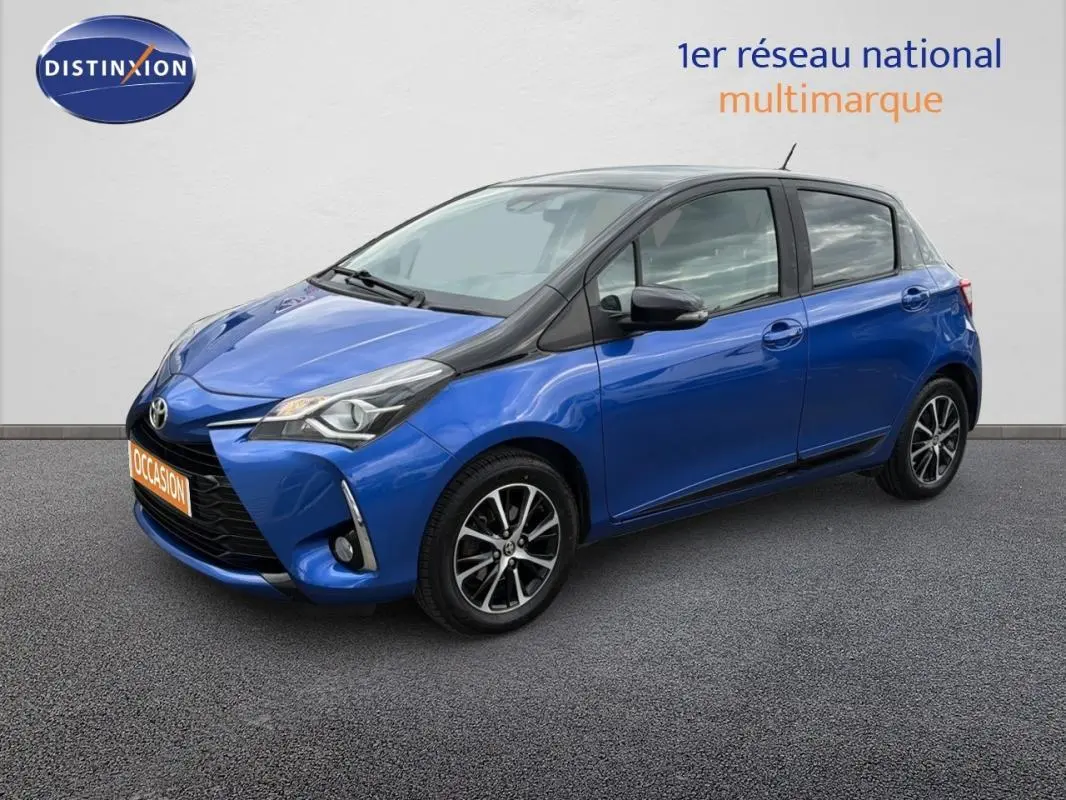 Toyota Yaris bleu foncé vue 3/4 avant droit, avec jantes alliage et phares antibrouillard visibles.
