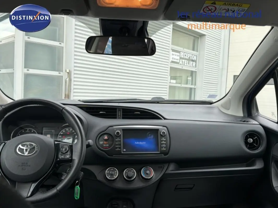 Vue intérieure avant de la Toyota Yaris MC2 69 VVT-i Design 2018, tableau de bord avec écran tactile et volant multifonctions noir.