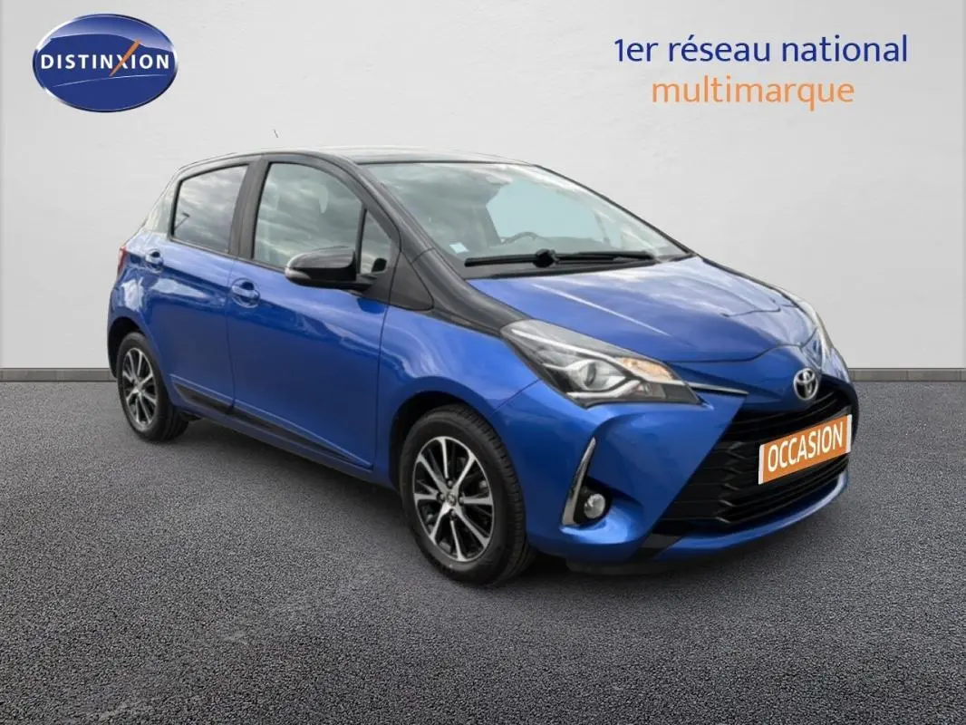 Toyota Yaris bleu foncé en 3/4 avant droit, avec jantes alliage et phares antibrouillard visibles.