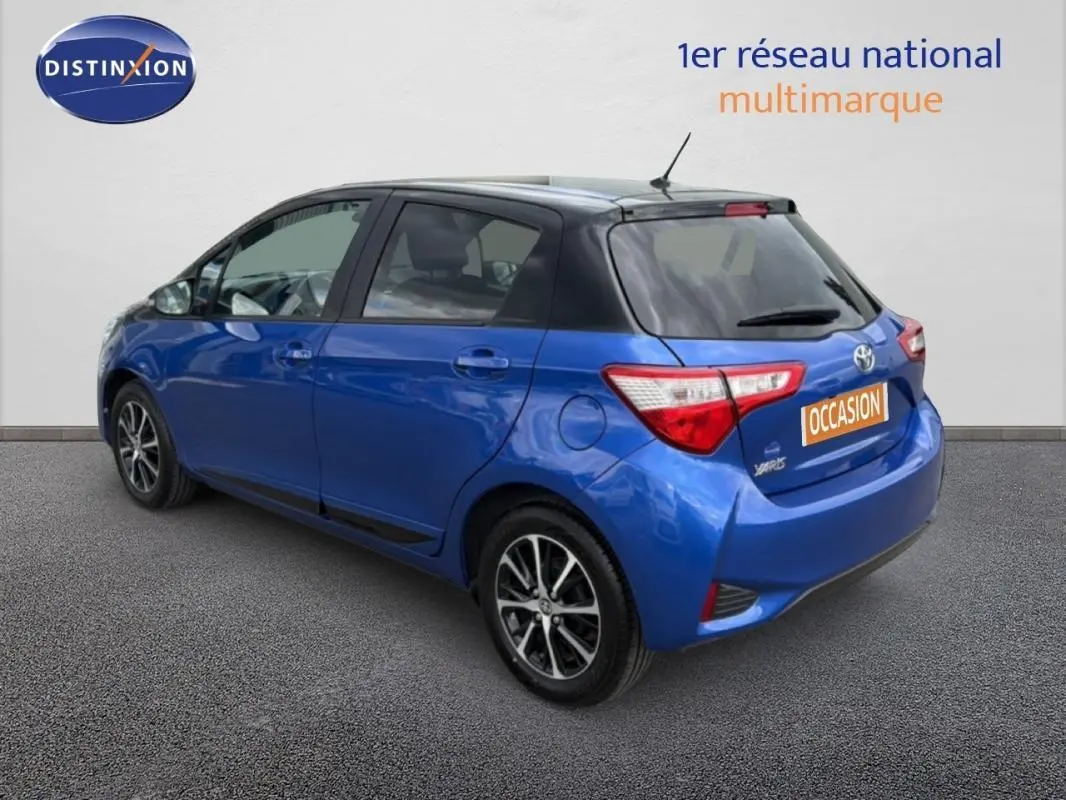 Vue 3/4 arrière droite d'une Toyota Yaris bleu foncé avec jantes alliage et feux arrière distinctifs.