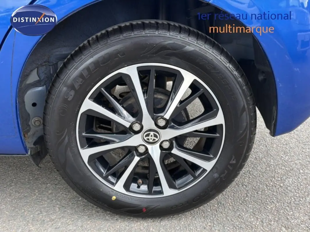 Gros plan sur la jante alliage 15 pouces noire et argent d'une Toyota Yaris bleu foncé, côté arrière droit.