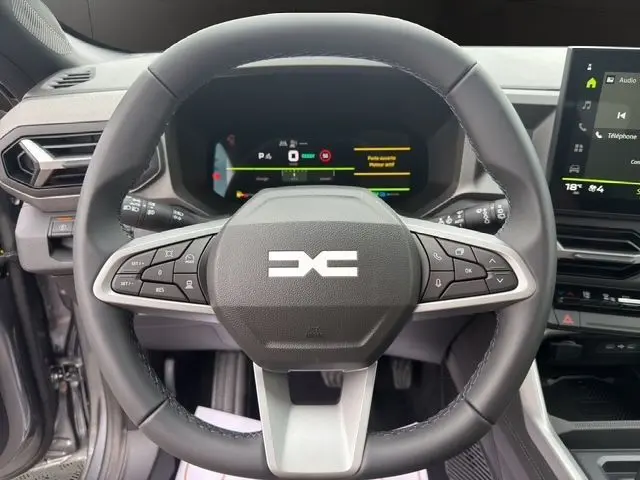 Vue rapprochée du volant cuir synthétique du Dacia Bigster Extreme Hybrid 155 avec tableau de bord numérique et écran tactile.