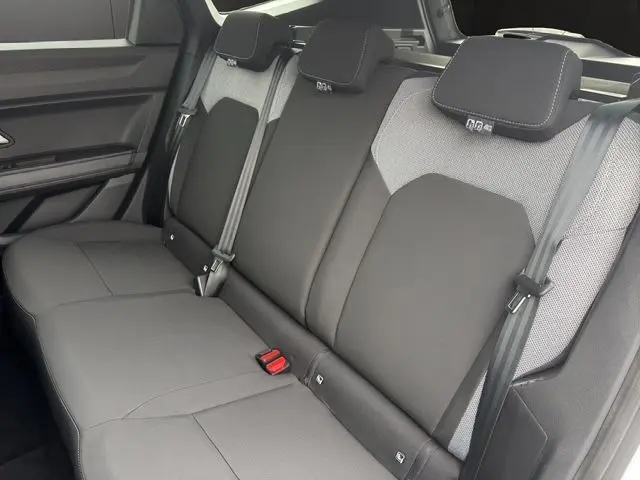 Vue intérieure du siège arrière gris foncé et clair du Dacia Bigster Extreme Hybrid 155 avec appuie-têtes et ceintures visibles.