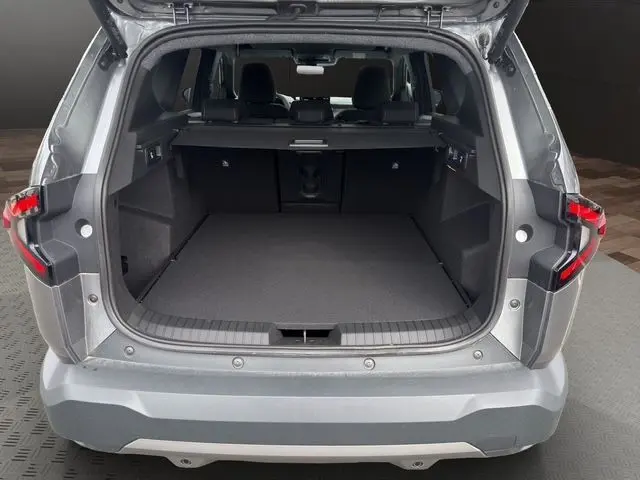Vue arrière ouverte du coffre spacieux du Dacia Bigster gris foncé, avec banquette arrière rabattable visible à l'intérieur.