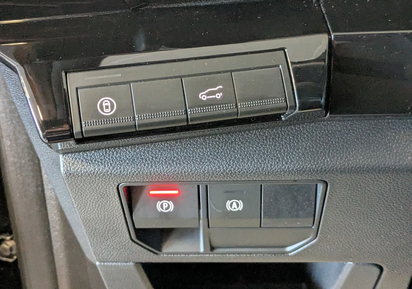 Gros plan sur les commandes intérieures du Renault Espace VI E-Tech, boutons de coffre et frein à main électronique.