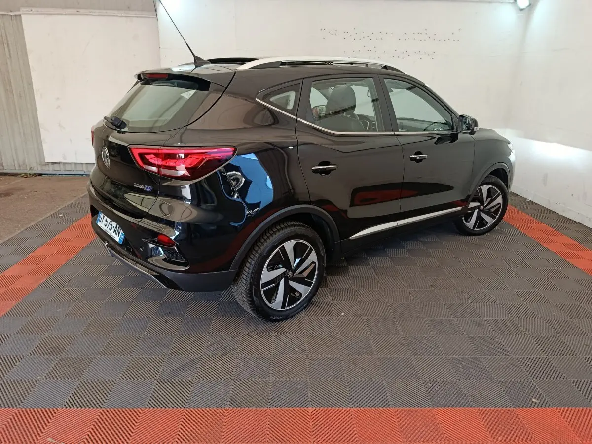 Vue 3/4 arrière droite du MG ZS Luxury 70kWh noir électrique, avec jantes distinctives et toit ouvrant visible.