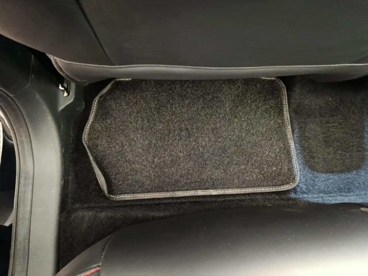 Vue plongeante sur le tapis de sol noir et la moquette du plancher côté passager arrière du MG Motor ZS Luxury 2024.