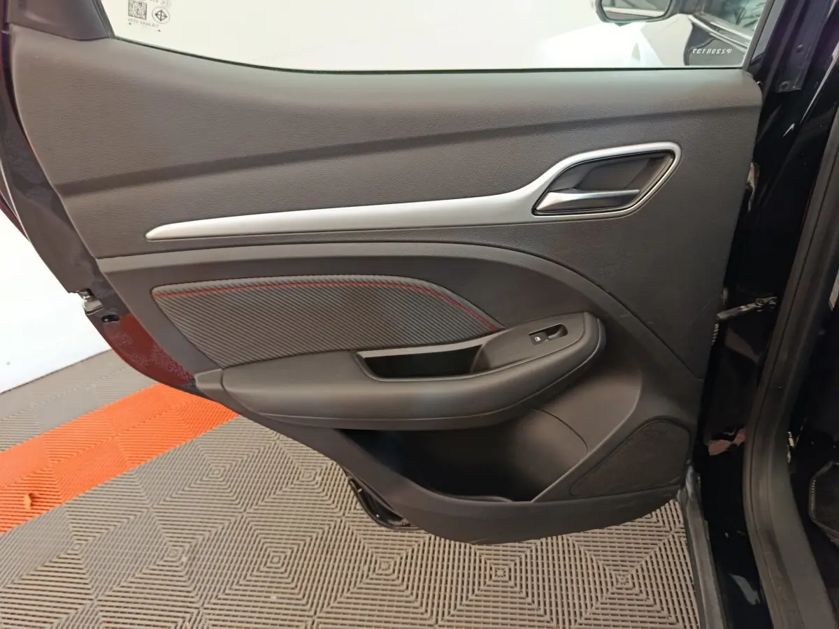Vue intérieure de la porte arrière gauche noire du MG Motor ZS Luxury 2024 avec insert décoratif et bouton de vitre électrique.