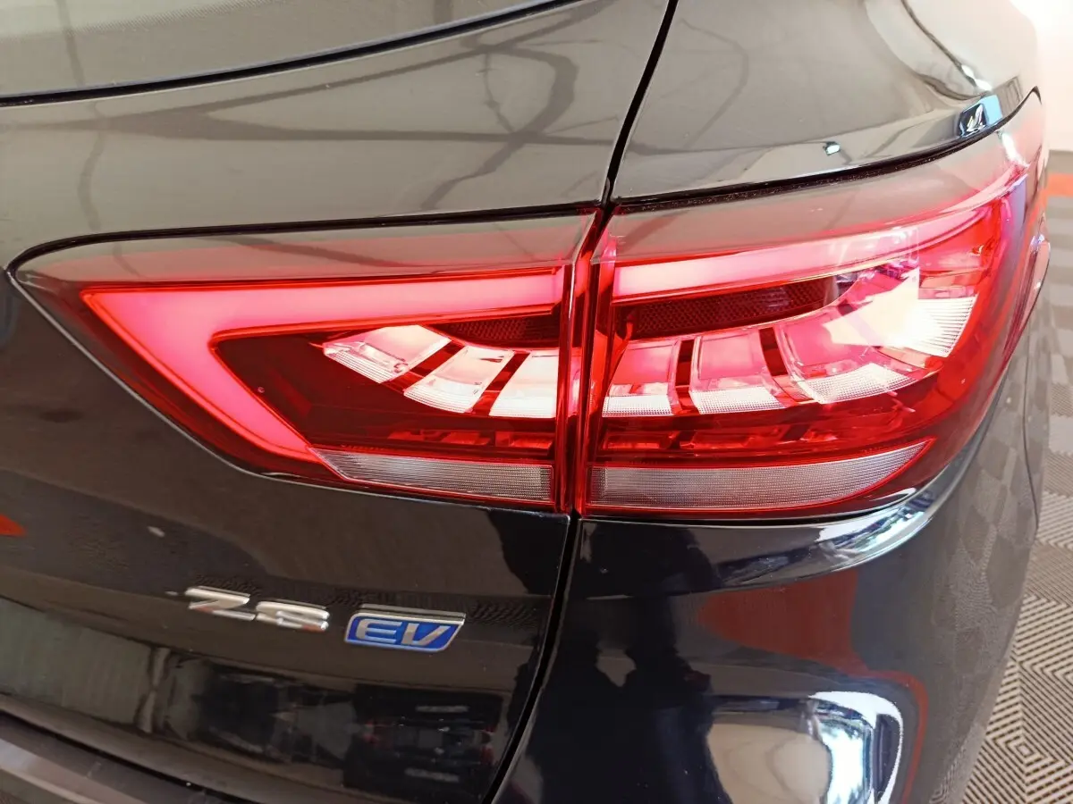 Gros plan sur le feu arrière droit rouge vif du MG ZS Luxury 70kWh noir électrique avec logo EV visible.