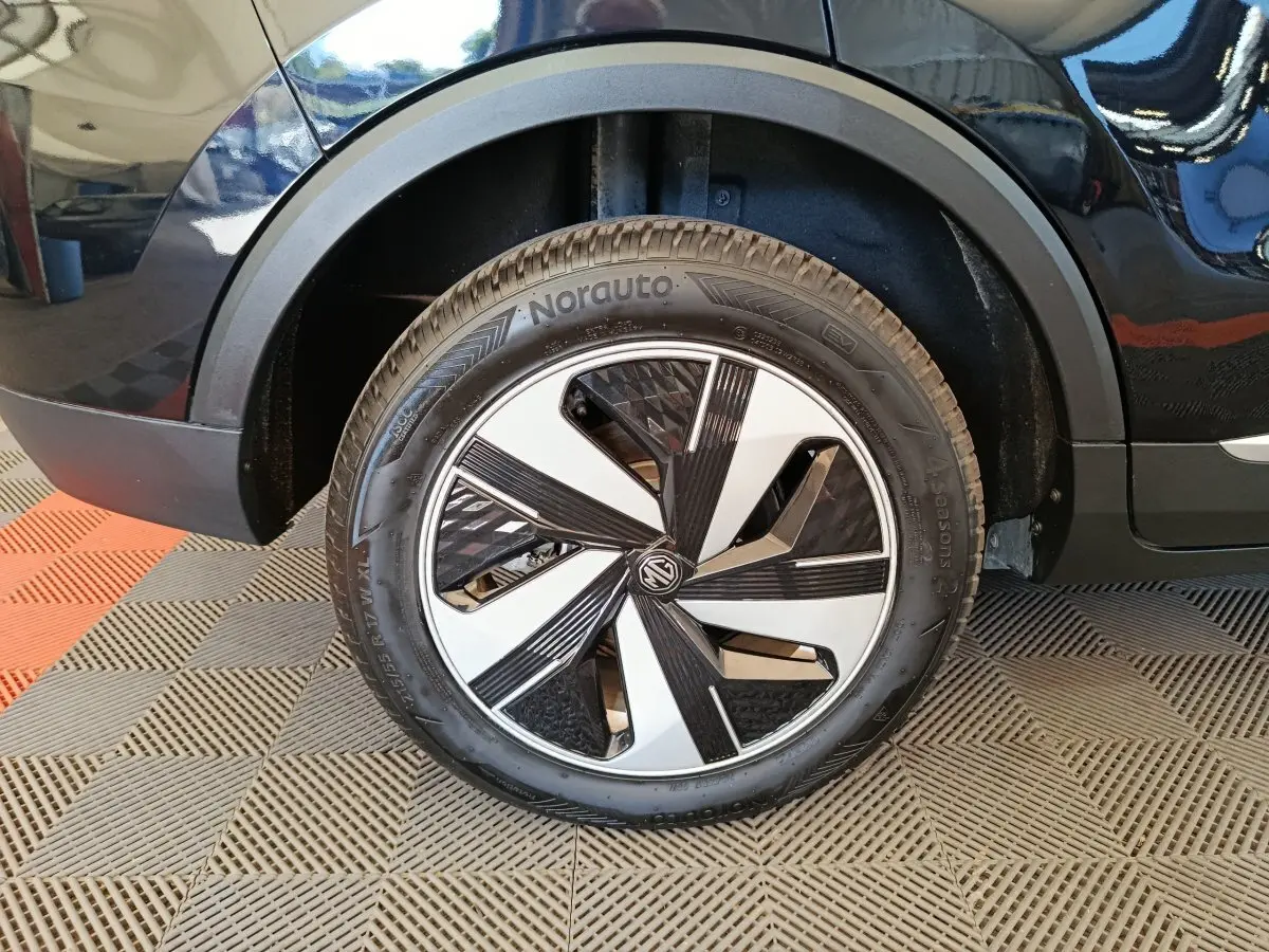 Gros plan sur la roue arrière droite du MG ZS Luxury 70kWh noir avec jante au design moderne bicolore.