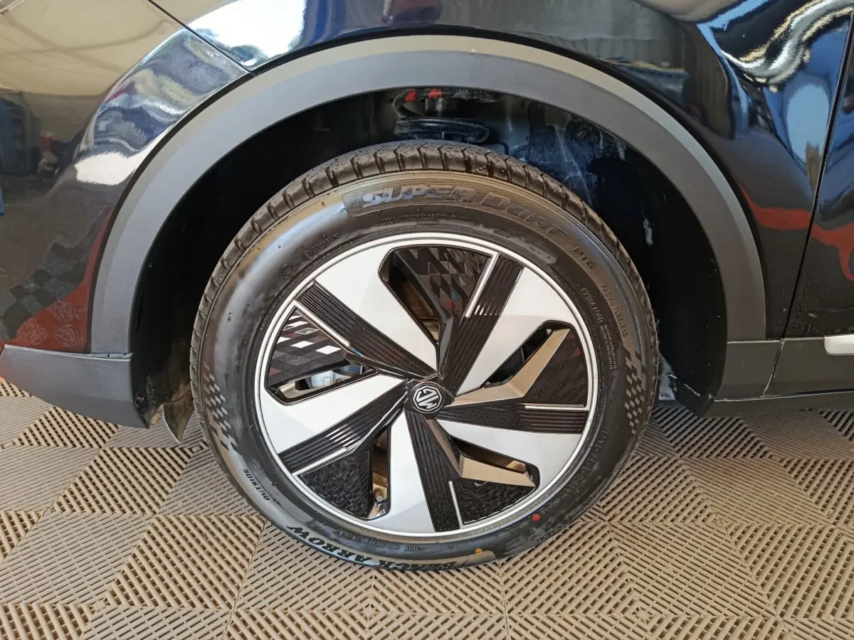 Gros plan sur la roue avant droite noire du MG ZS Luxury 70kWh 2024 avec jante bicolore au design géométrique.