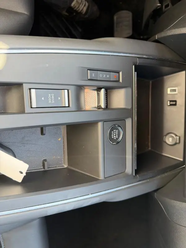 Vue rapprochée de la console centrale noire du Citroën C5 Aircross 2024 hybride, avec bouton start/stop et sélecteur de mode de conduite.