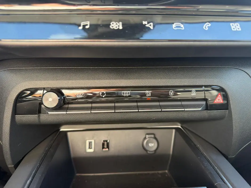 Gros plan sur la console centrale du Citroën C5 Aircross Hybride 2024 noire, montrant les commandes climatisation et ports USB.