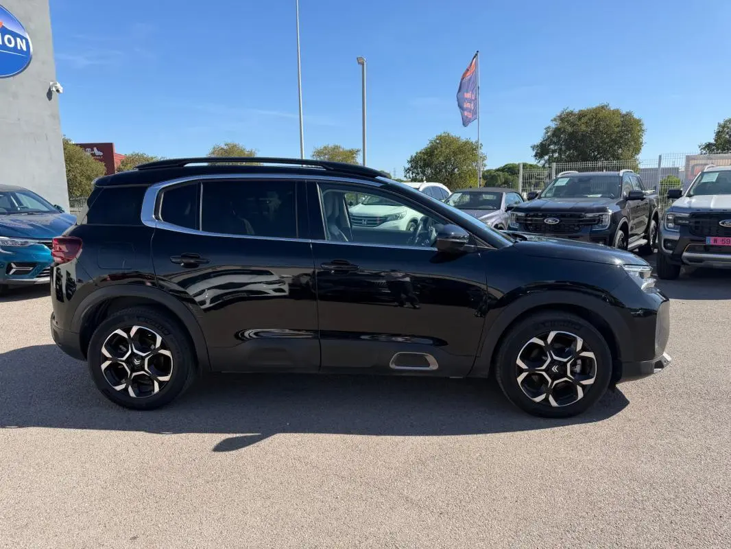Vue de profil côté gauche d'un Citroën C5 Aircross hybride noir 2024 avec jantes distinctives à motifs géométriques.