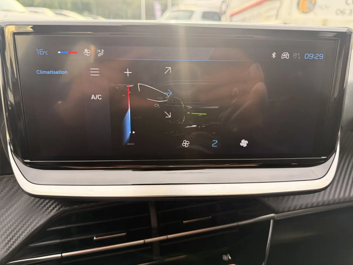 Écran tactile central affichant la climatisation dans l'habitacle d'une Peugeot 208 blanche de 2025.