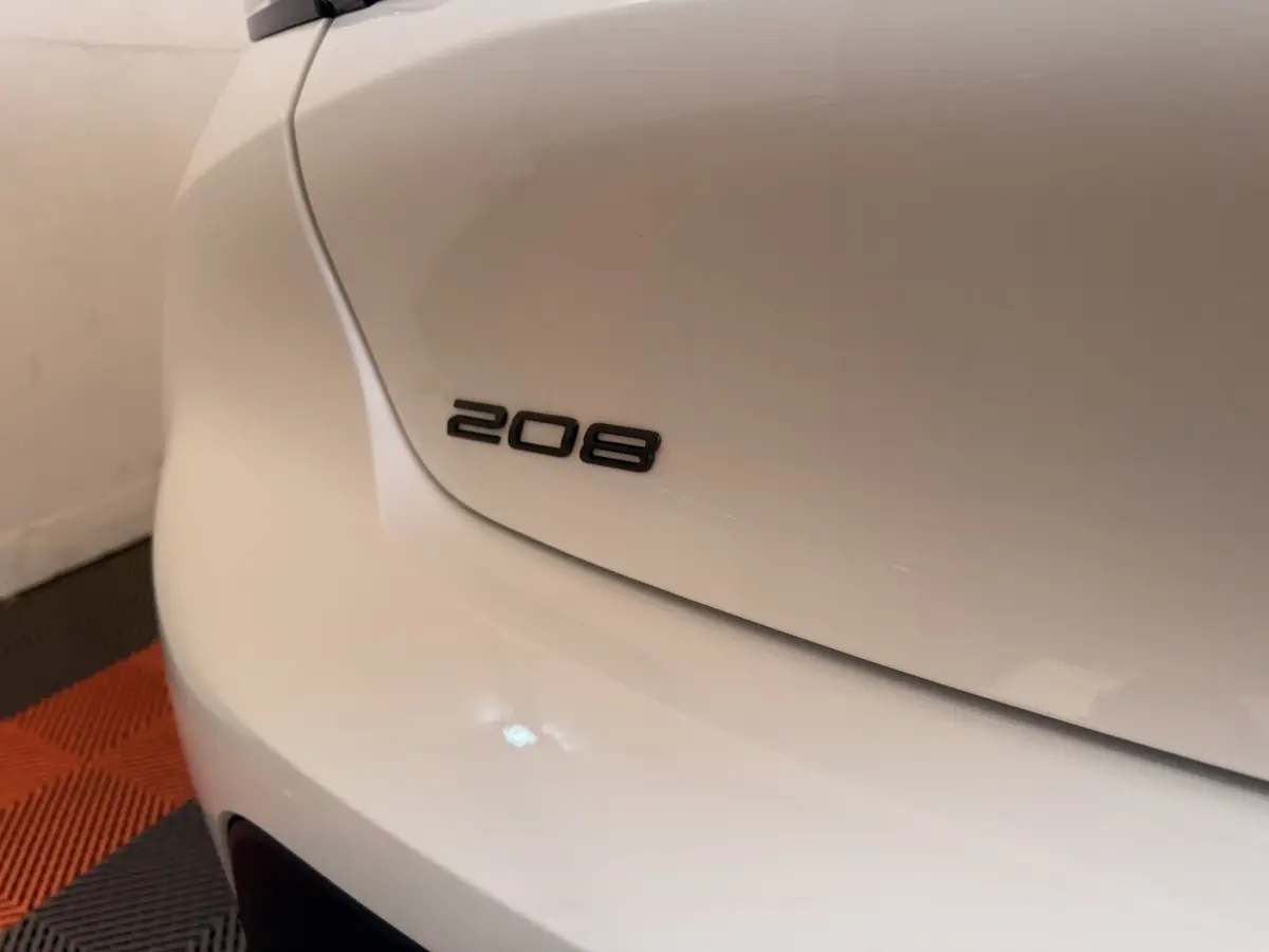 Gros plan sur l'arrière gauche blanc d'une Peugeot 208 avec le logo 208 visible sur le coffre.