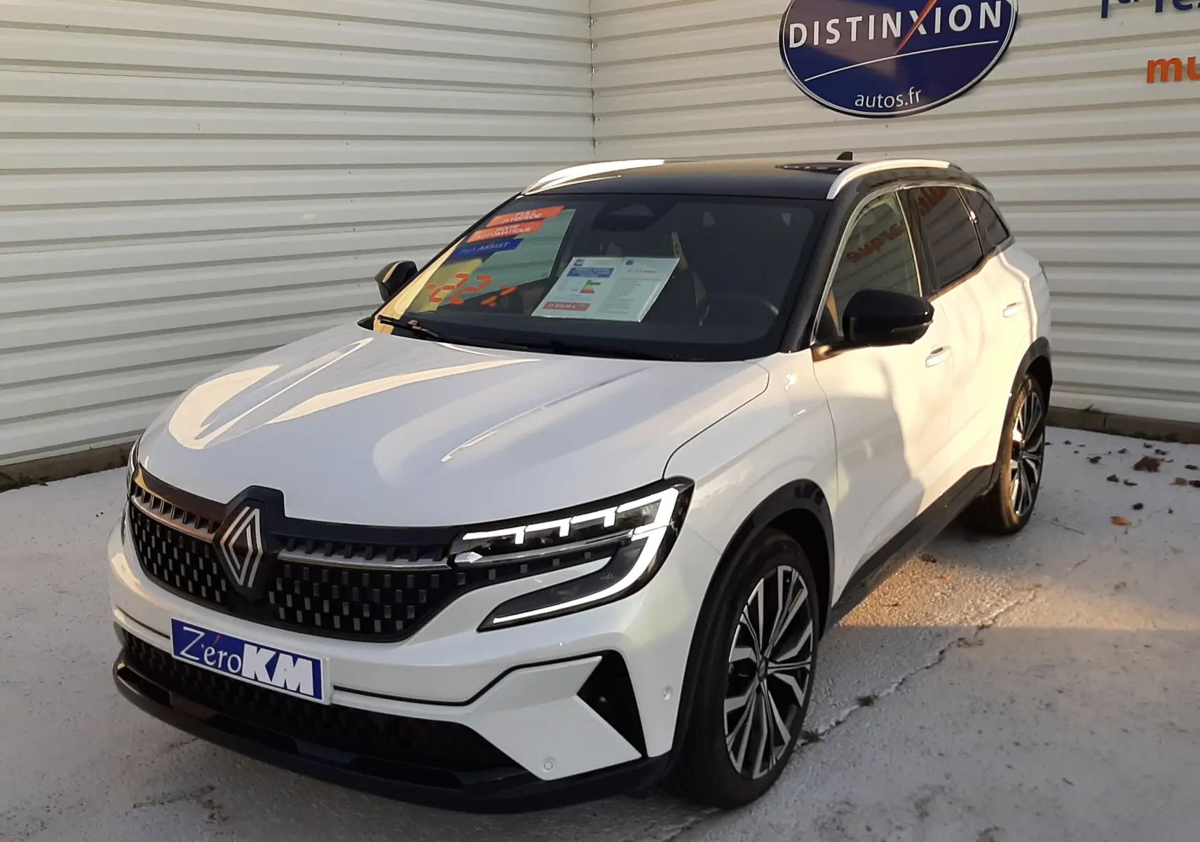 Renault Austral E-Tech Full Hybrid 200 Iconic blanc nacré avec toit noir, vue 3/4 avant droit, calandre et phares LED distinctifs.