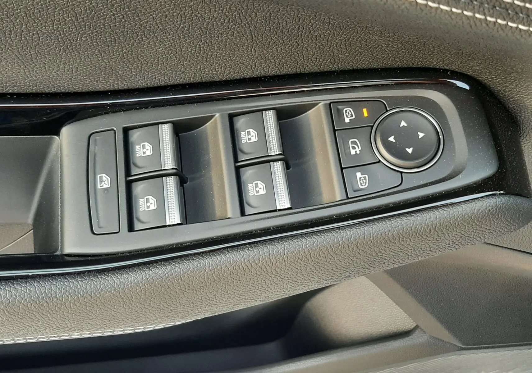 Gros plan sur les commandes des vitres et rétroviseurs côté gauche d'un Renault Austral 2025 blanc nacré au toit noir.