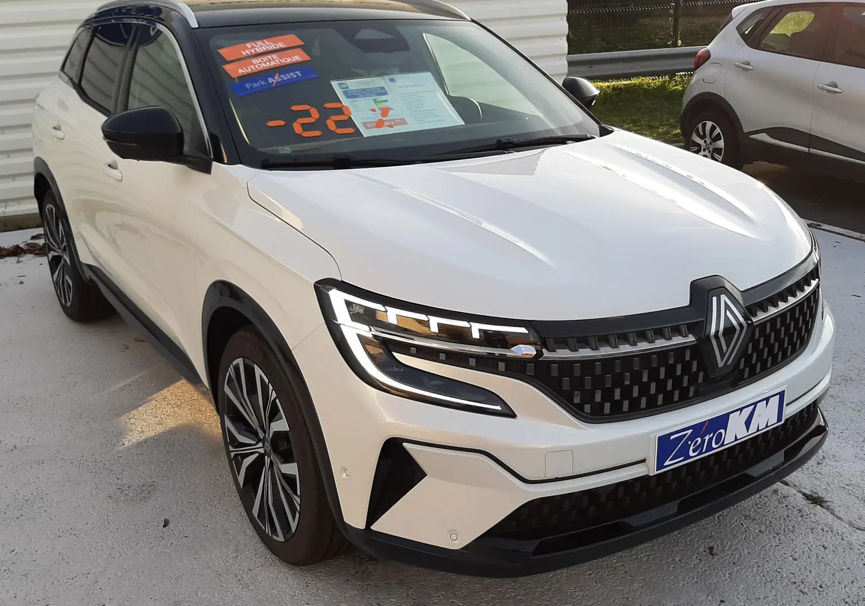 Renault Austral E-Tech hybride blanc nacré avec toit noir, vue 3/4 avant mettant en valeur sa calandre et ses phares LED.