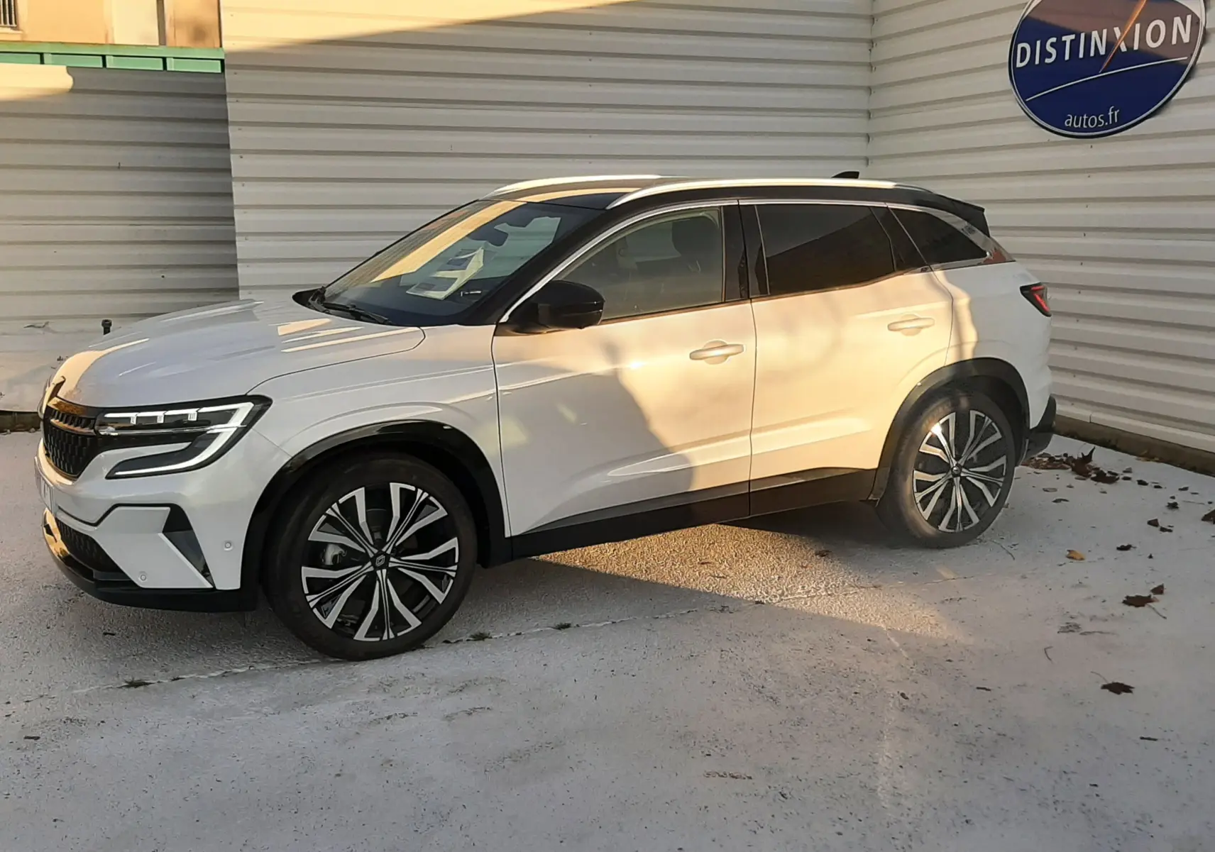 Renault Austral E-Tech Full Hybrid 200 Iconic blanc nacré avec toit noir, vue de profil côté gauche en extérieur.