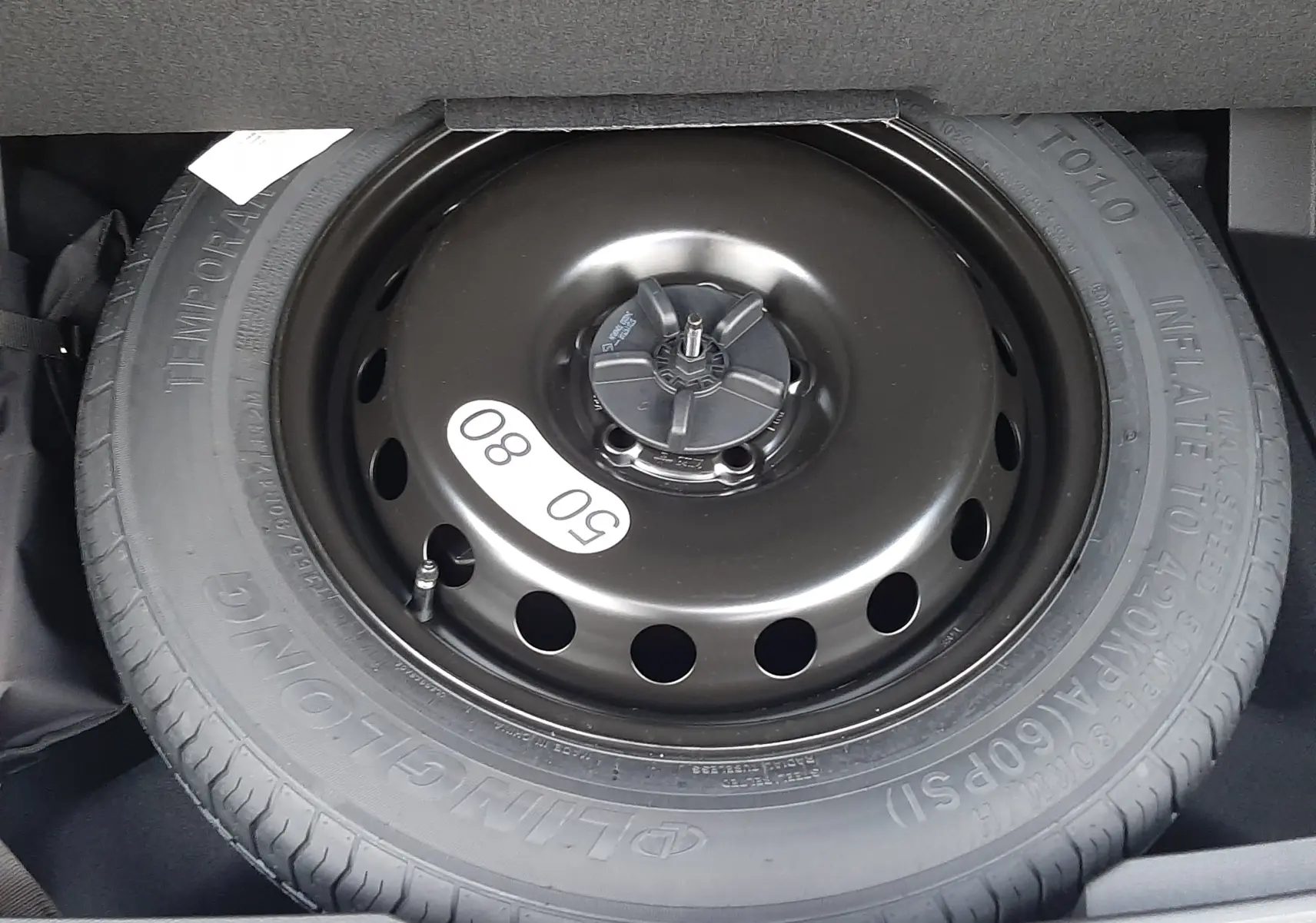 Roue de secours provisoire noire en gros plan dans le coffre du Renault Austral 2025 blanc nacré toit noir.