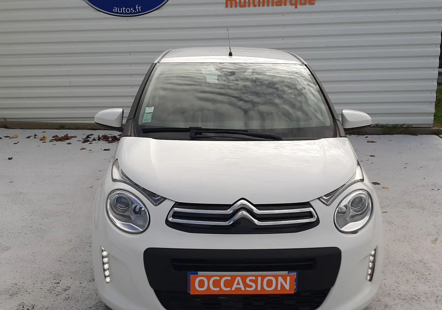 Vue frontale d'une Citroën C1 blanche 2021 avec feux diurnes LED allumés et plaque "OCCASION" visible.