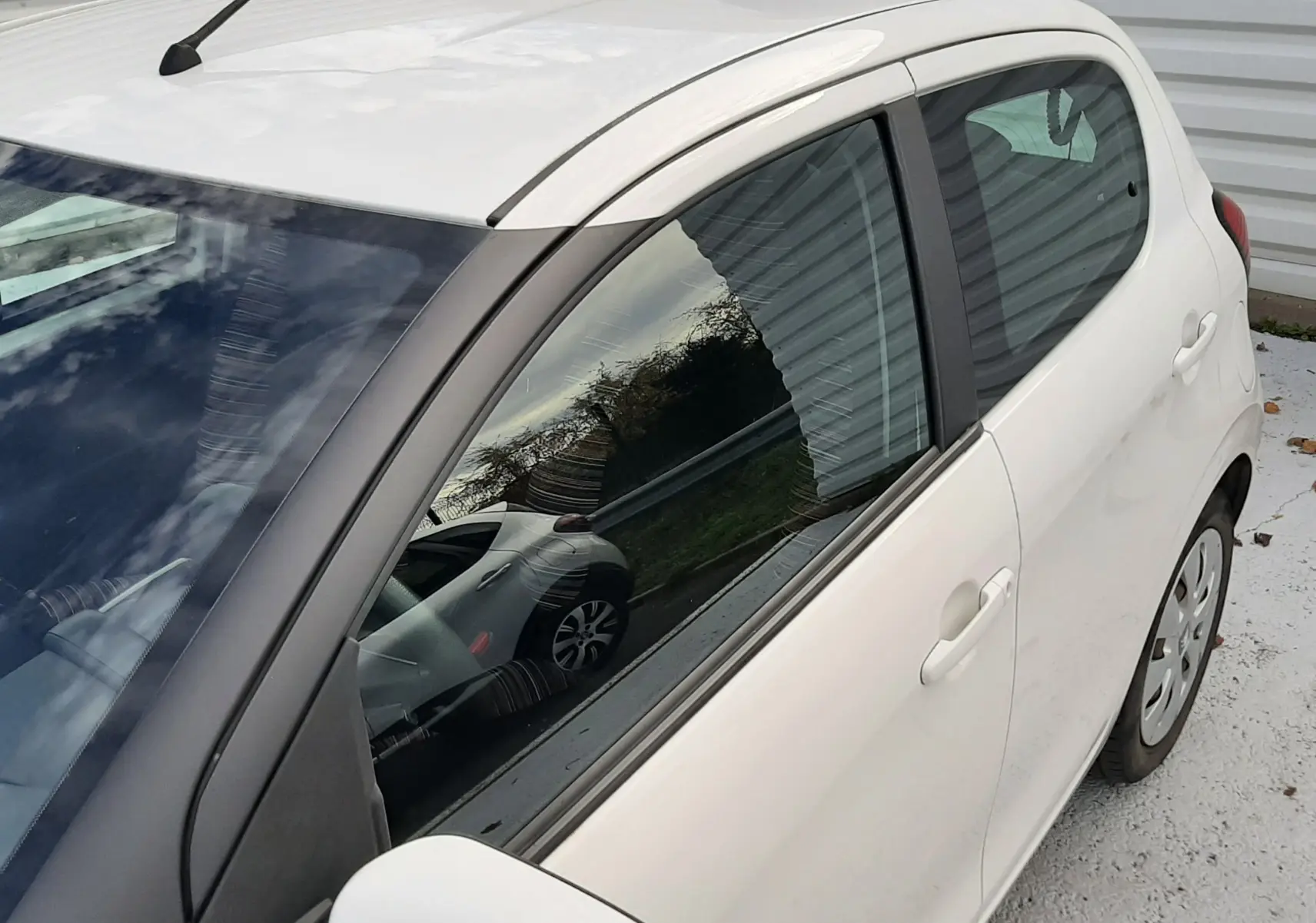 Vue de côté droit d'une Citroën C1 blanche 5 portes, mettant en valeur la carrosserie compacte et les vitres teintées.